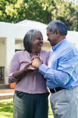 Fototapeta premium Elderly couple laughing and holding hands outdoors, enjoying sunny day together