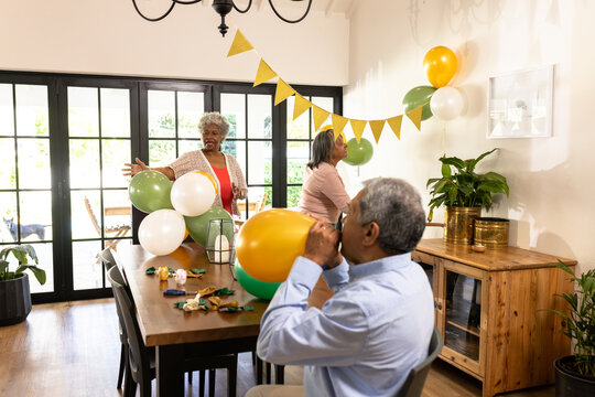 Decorating for party, diverse group inflating balloons and hanging banners at home