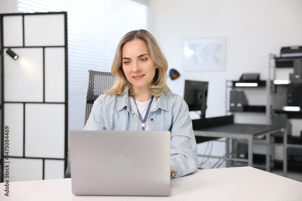 Poster smiling engineer working with laptop at table in office
