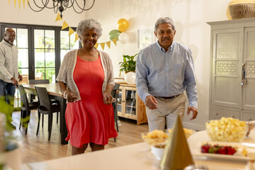 Elderly couple joyfully dancing at home during festive celebration with friends © WavebreakMediaMicro