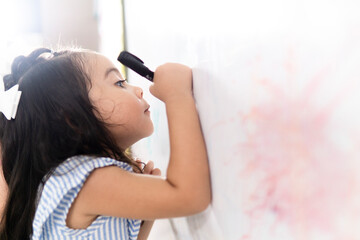 Cute toddler girl drawing on whiteboard in kindergarten classroom