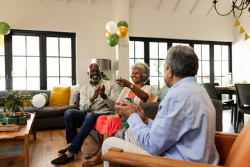 Celebrating together at home, elderly friends clapping in festive atmosphere