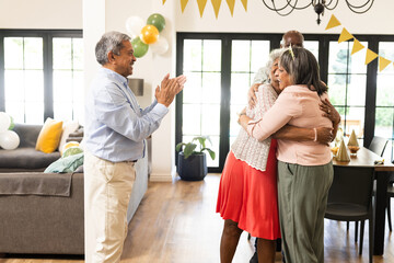 Family celebrating at home, hugging and clapping with joyful expressions