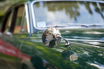 Green vintage car with round chrome side mirror. Green classic car with a round chrome side mirror...