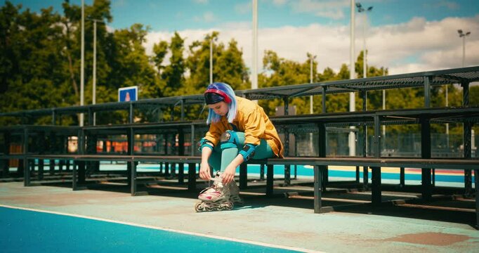 Teenager Roller Skater Girl with Blue Hair Puts on Rollerblades at Skate Park. Training Hobby Active Lifestyle Youth Culture Concept
