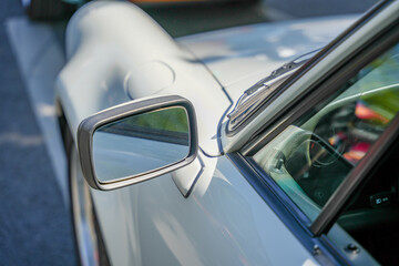 Side mirror of white sports car. Side view mirror of a sleek white sports car, highlighting...