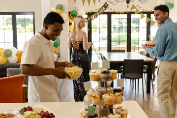Friends celebrating birthday at home, enjoying snacks and desserts with laughter