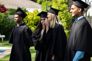 Graduates in caps and gowns celebrating together outdoors, smiling and joyful