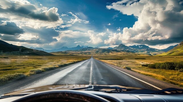 A road with a long stretch of highway in the distance. The sky is cloudy and the road is wet