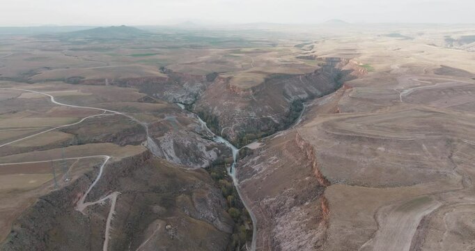 Drone approaches rock formations and settlement in Kayseri Soğanlı Valley. Natural rock formations and historical textures stand out throughout the valley.