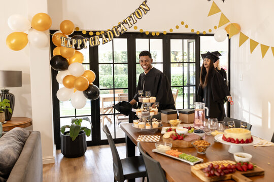 Graduates celebrating at home with food and decorations, smiling and enjoying moment