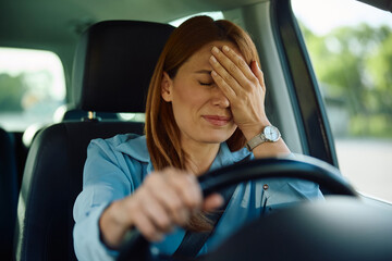 Upset woman behind the steering wheel of car.