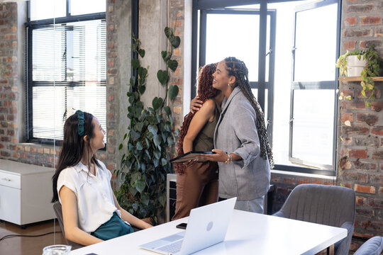 Colleagues celebrating success with warm hug in modern office setting