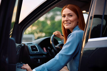 Happy woman going on road trip by car and looking at camera.
