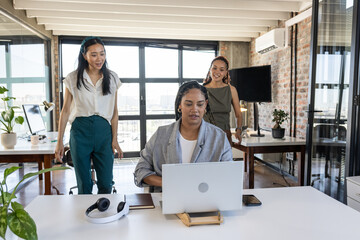 Fototapeta premium Celebrating success, colleagues smiling and discussing project around laptop in office