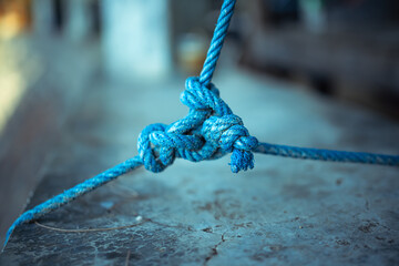 A close-up image showing the texture of braided blue rope tied into a knot. Great metaphor for business teamwork.
