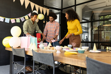 Celebrating baby shower, colleagues arranging gifts and decorations together in office
