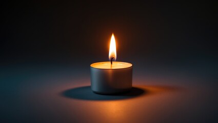 Darkness surrounds a small burning tea candle
