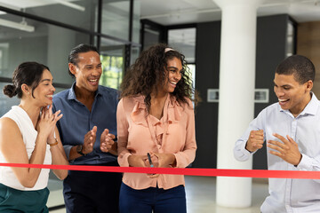Diverse business team celebrating ribbon-cutting ceremony with excitement and joy