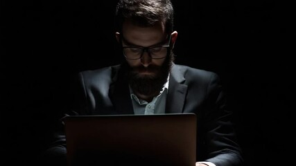 Focused businessman intensely working on laptop in dark office, coding late at night - Powered by Adobe