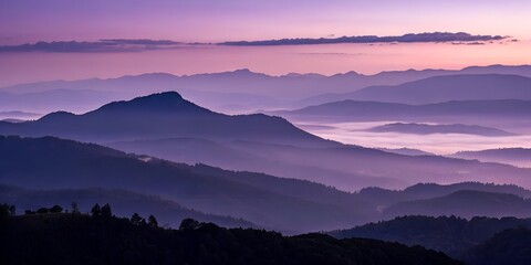 Obraz premium Serene mountain range landscape displays a captivating purple and violet sunrise with layers of misty fog and silhouettes