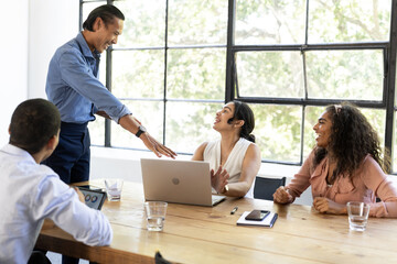 In meeting, diverse team discussing ideas around laptop, collaborating and smiling