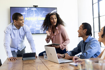 Diverse business team discussing project strategy with laptops and tablets in office