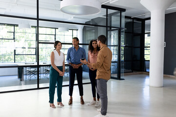 Fototapeta premium Diverse business team discussing project in modern office, standing and smiling