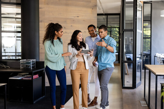 Diverse business team discussing project while walking through modern office hallway
