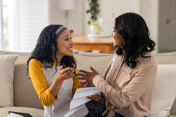 On couch at home, mother and child sharing joyful conversation, discussing documents