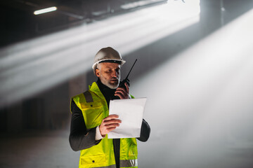 Construction foreman giving instructions over radio during building inspection.