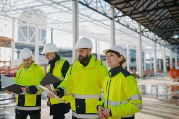 Team of engineers and construction workers inspecting building progress.