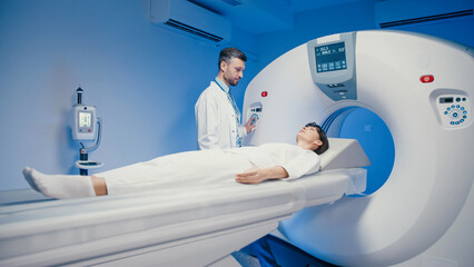 Caucasian woman lying still on CT scanner bed sliding into machine for diagnostic imaging. Focused...