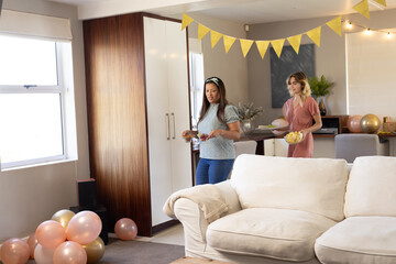 Women preparing for party at home, arranging balloons and decorations cheerfully