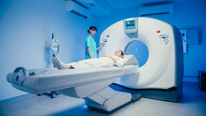 Calm medical operator pressing control panel while overseeing patient entering CT scanner....