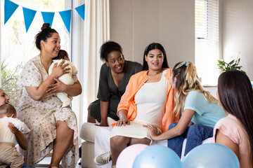 Women celebrating baby shower, smiling and chatting with balloons and decorations