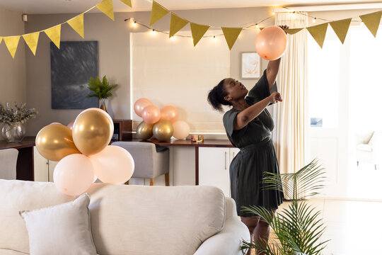 Decorating living room with balloons, woman preparing for festive celebration