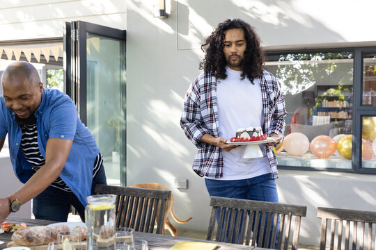 Naklejki Carrying cake and arranging decorations, friends setting outdoor table for celebration