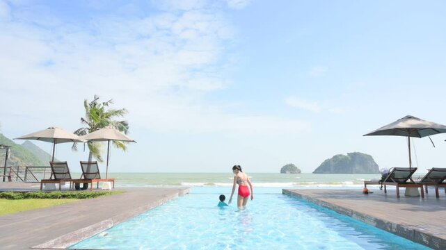 Poolside Leisure: A moment of pure joy captured poolside as a parent guides a child in the refreshing water under the sun, offering a breathtaking panorama of the sea.