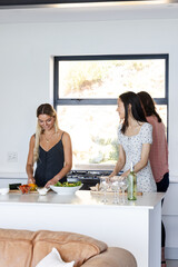 Preparing salad together in kitchen, friends sharing conversation and laughter