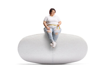 Woman sitting on a slimming pill and measuring waist