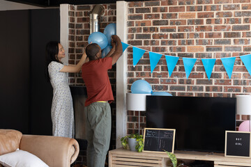 Couple decorating living room with blue balloons and banners for celebration