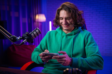 Young Man Enjoys Gaming Session on Smartphone at Stylish Setup