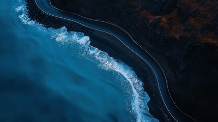 A coastal road curving along ocean waters and dark cliffs