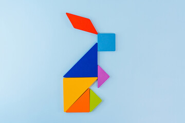 Tangram puzzle depicting a rabbit or a hare on a blue background, conceptual image, place for text