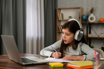Young Girl Studying Diligently at Home Wearing Headphones