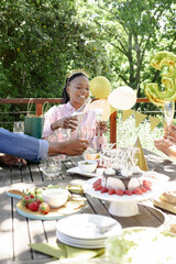 Pouring champagne outdoors, woman celebrating birthday with balloons and cake