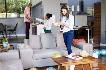 Obraz premium Woman preparing snacks in living room while friends setting up for celebration