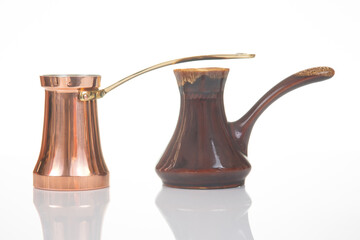 Two traditional coffee pots, one copper with a brass handle and another ceramic with a dark brown...