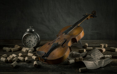 Violin resting on a wooden table with corks and an antique clock in a dimly lit room
